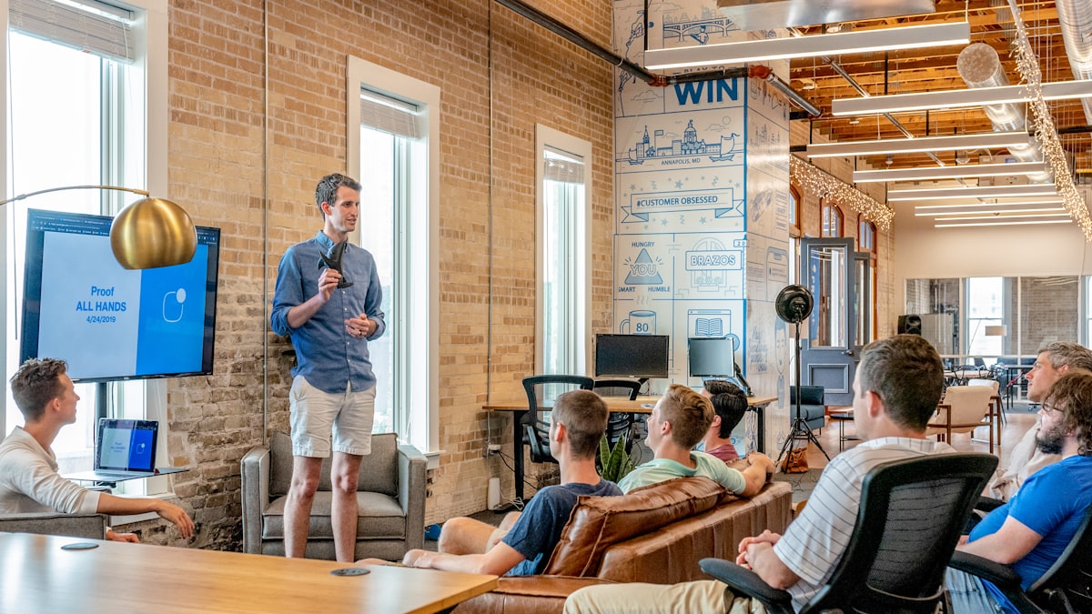A person presenting to a seated team in an open office