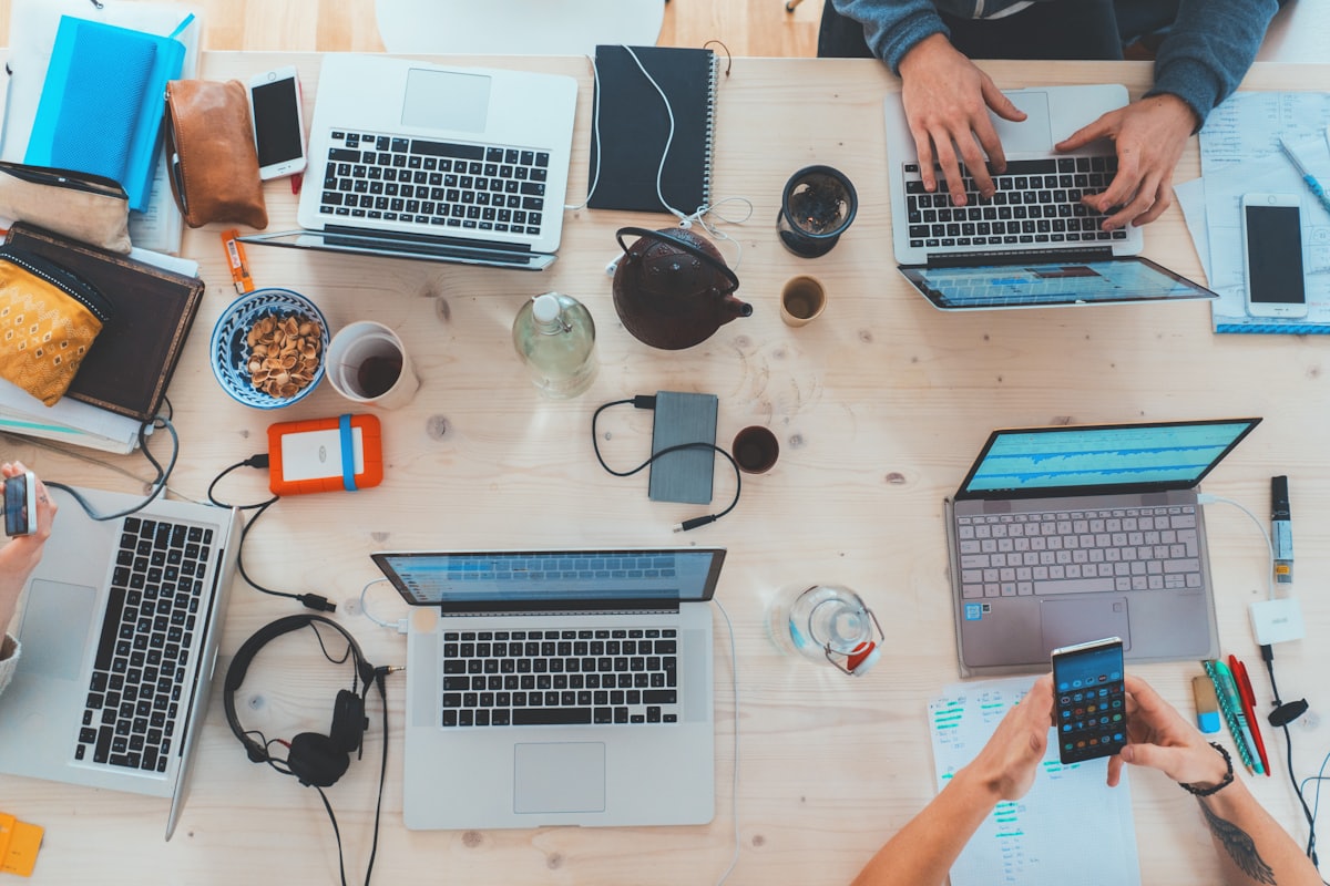 Laptops and hands around a shared work table, seen from above