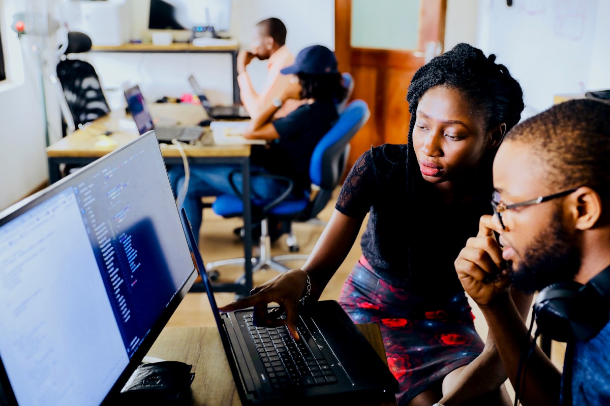 Two people working through a problem at one screen
